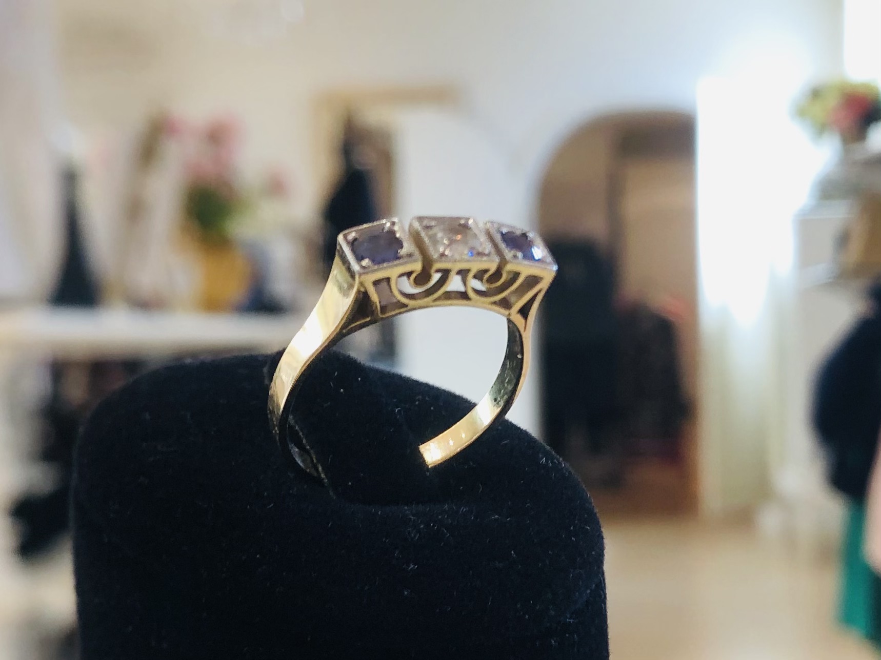 Goldring mit Diamant und Saphiren seitlich auf schwarzem Schmuckständer fotografiert