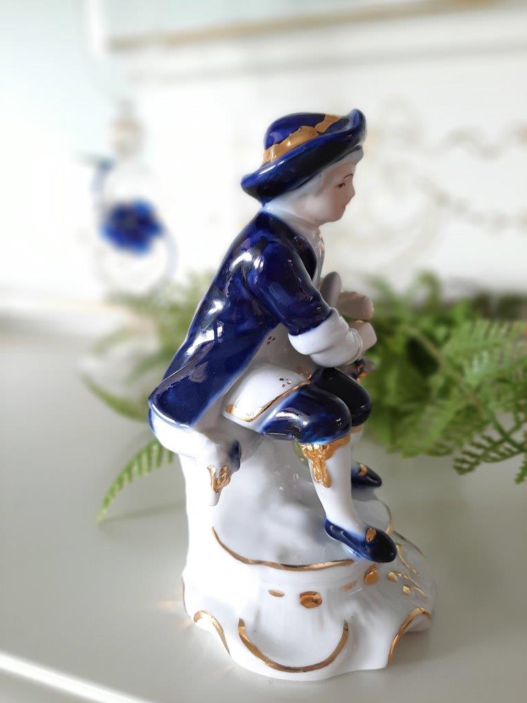 Seitenansicht einer Porzellanfigur eines sitzenden Mannes in Blau, Weiß und Gold