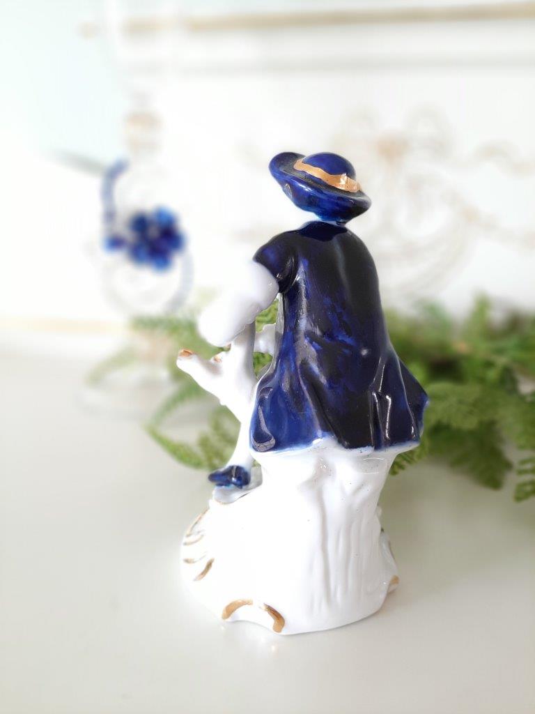 Porzellanfigur eines sitzenden Mannes auf Baumstumpf, Rückansicht, blau-weiß mit Gold