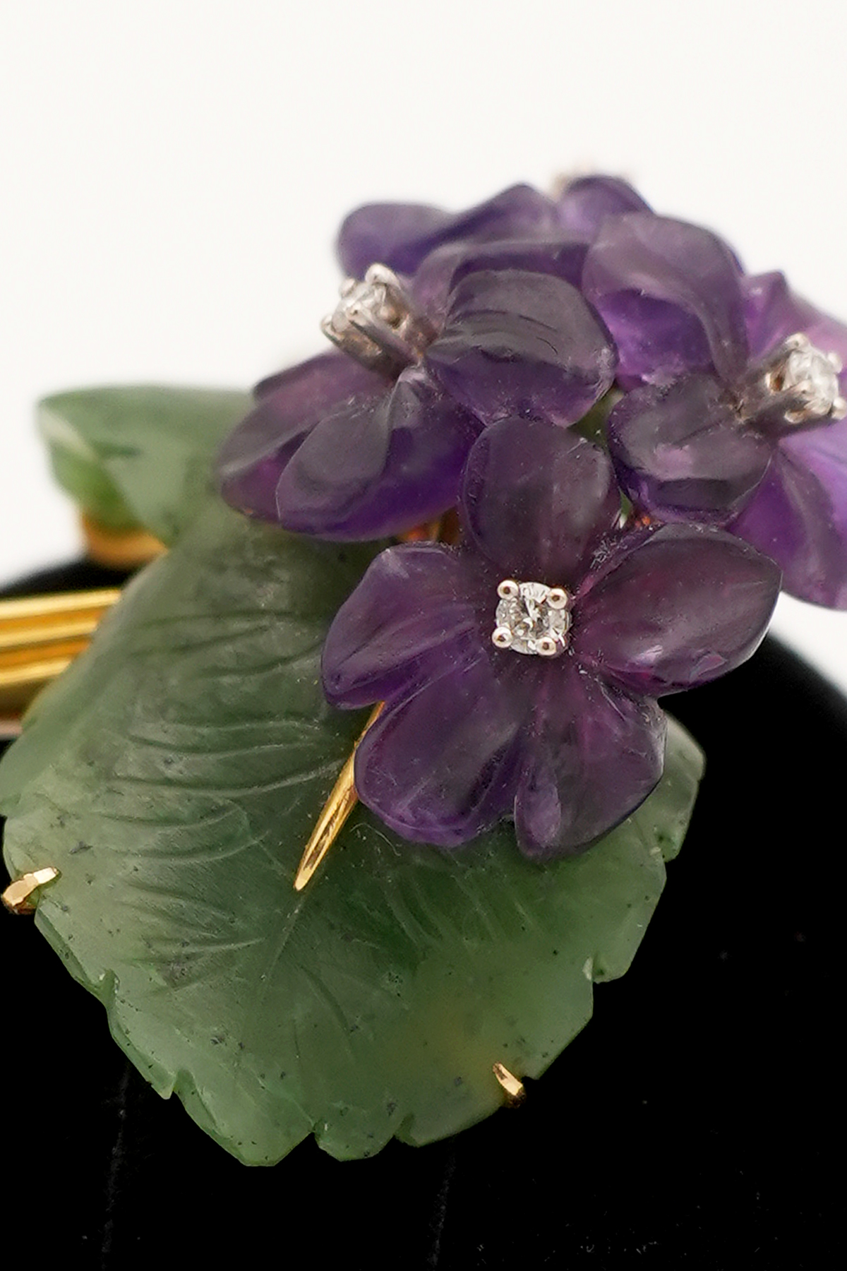 Blumenbrosche aus Gold mit violetter Blüte, grünen Blättern und funkelnden Diamanten in Nahaufnahme
