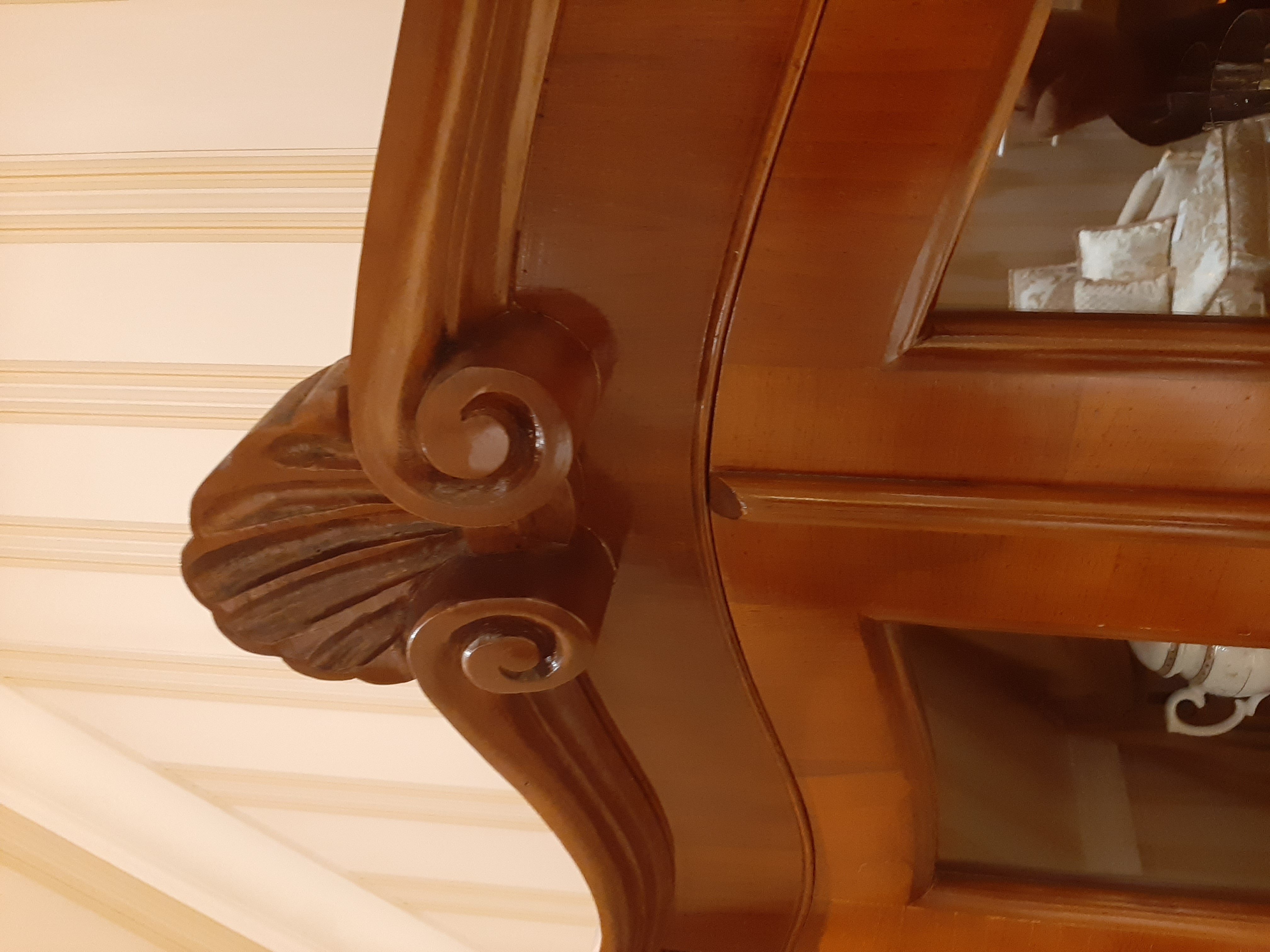 Detailaufnahme der geschwungenen Krone einer italienischen Barockvitrine aus Nussbaum