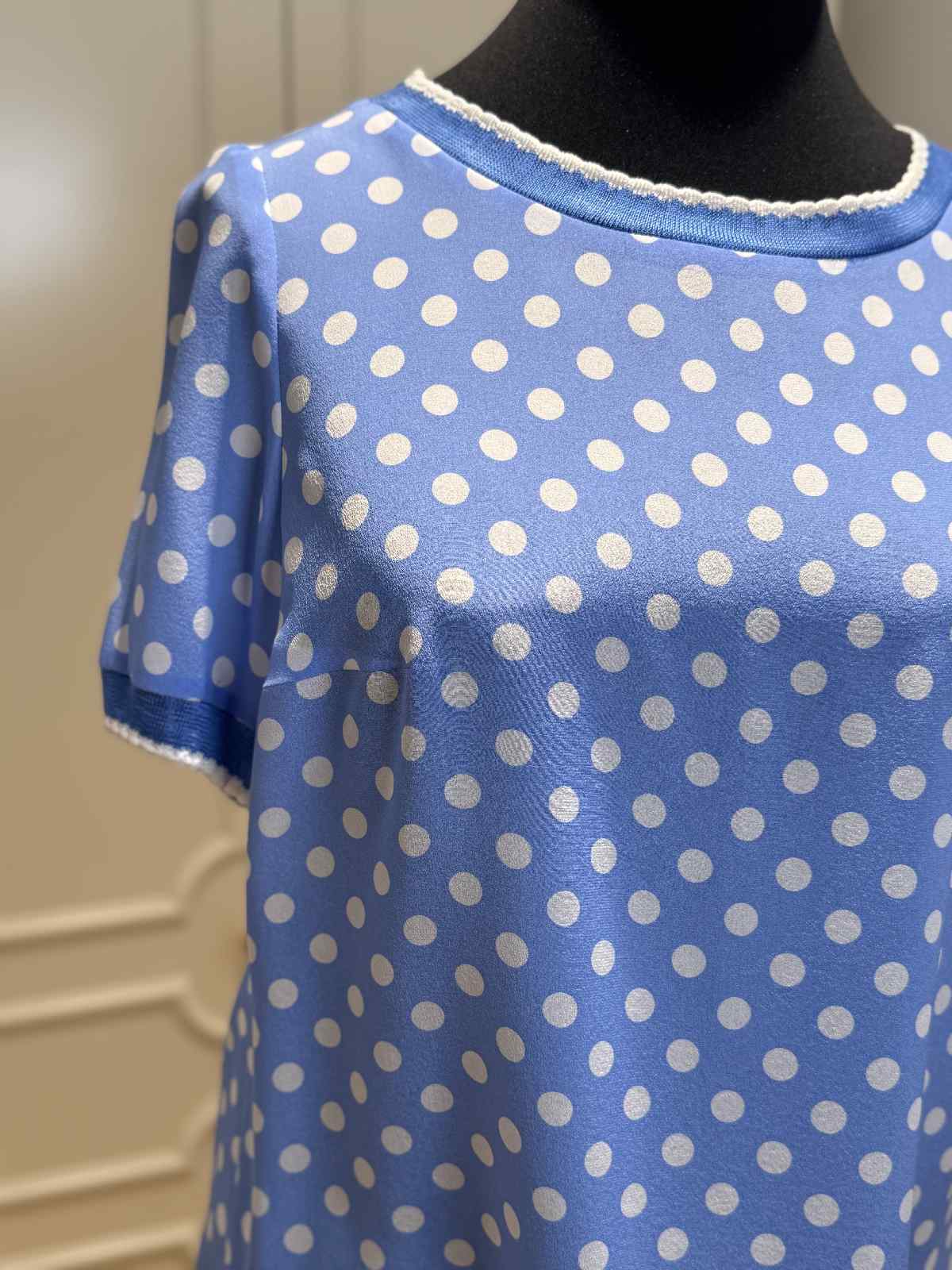 Detailansicht der Maison Common Seidenbluse in Blau mit feinem Polka-Dot-Muster und glattem Fall.