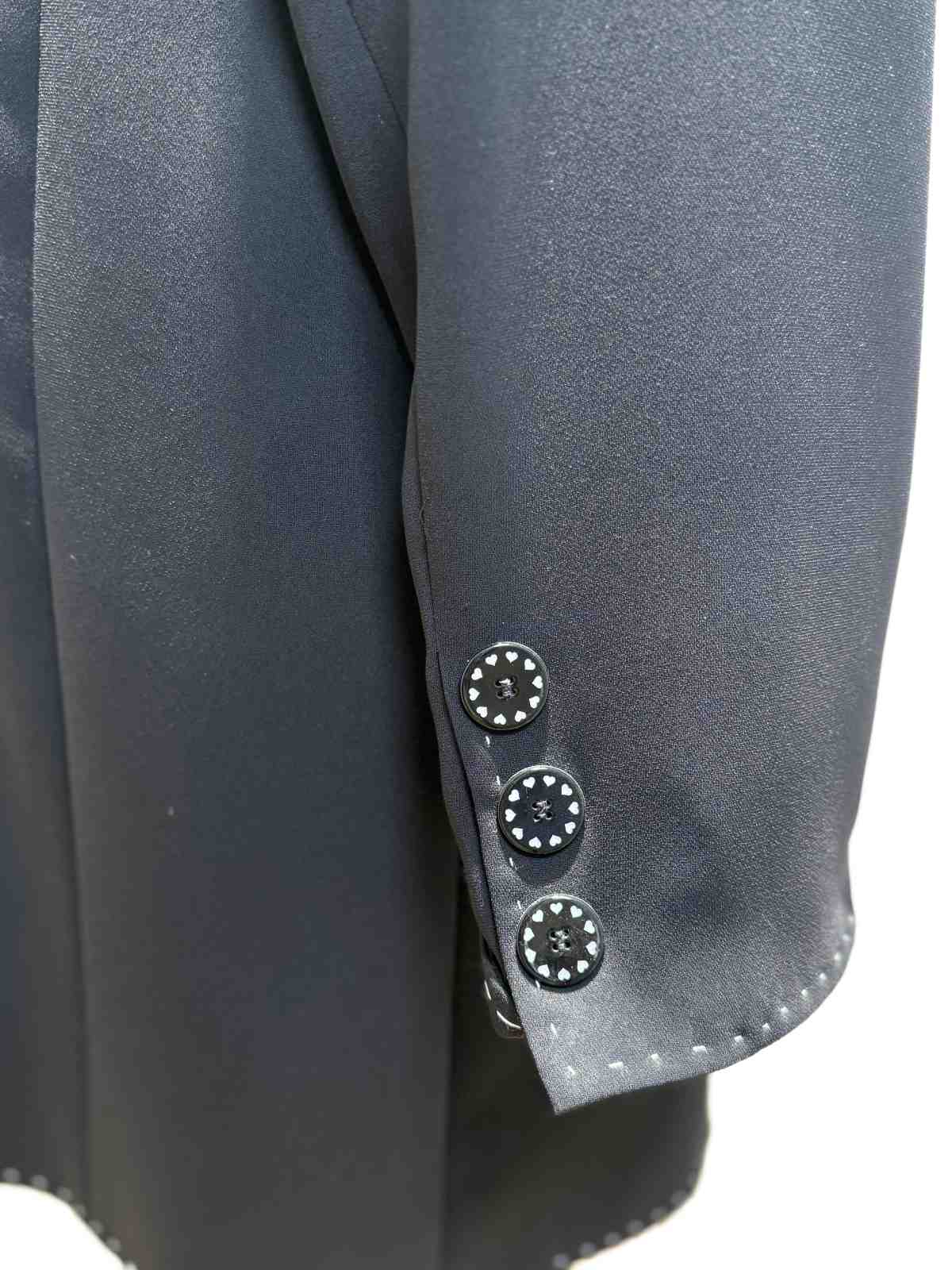 Detailaufnahme der dekorativen Knöpfe am Ärmel mit Herzmotiv.