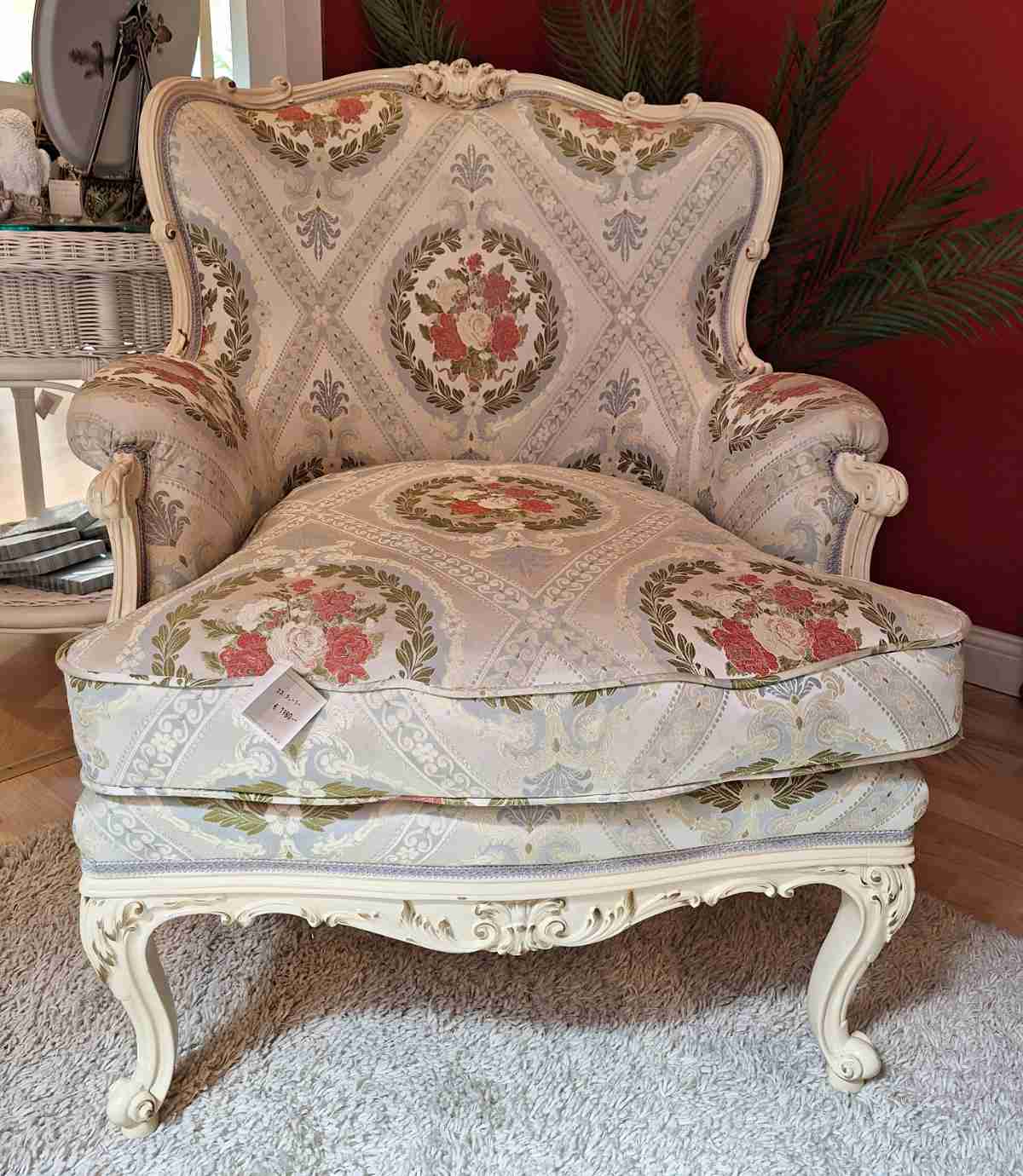 Cremefarbener Sessel, gebraucht, mit Ornamentstoff und Goldverzierungen, zierlich, Frontalansicht.