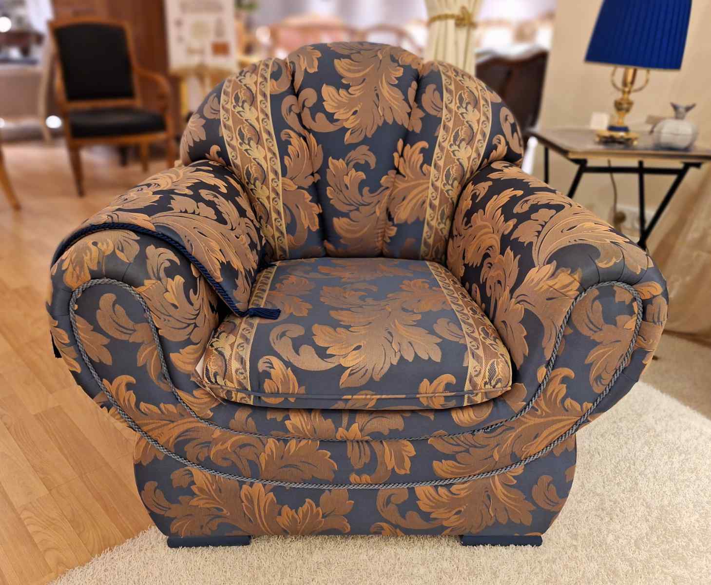 Außergewöhnlich geformter Sessel, mit blauem Ornamentstoff, komfortabler Sitz, hochwertig, Secondhand, Frontalansicht.