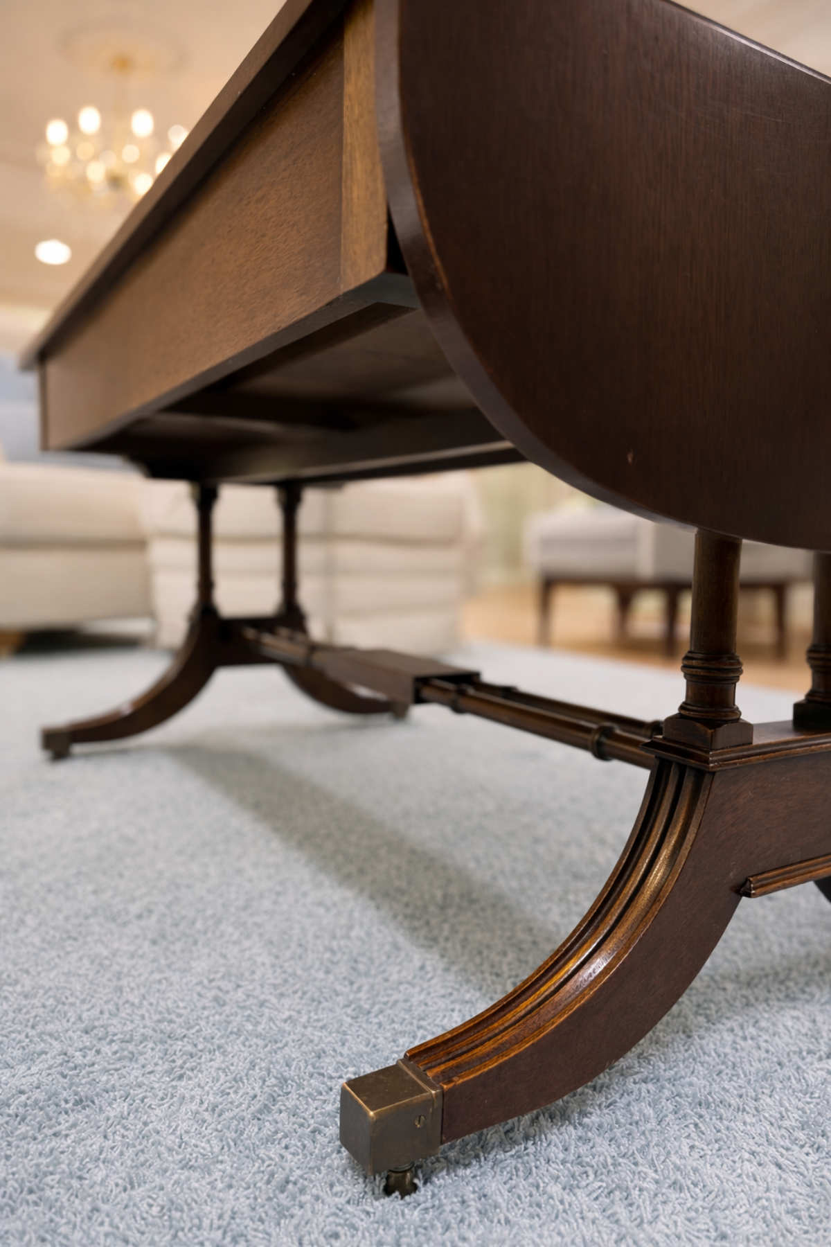 Detailaufnahme der geschwungenen Tischbeine aus Mahagoni mit Rollen.