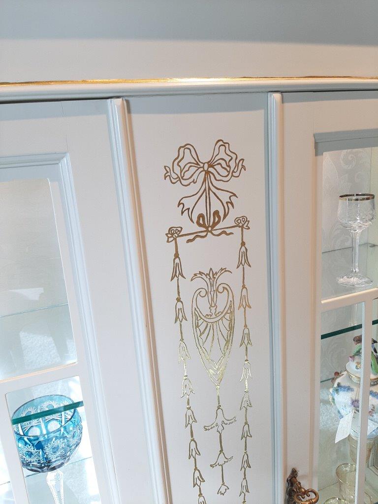Seitliches Detail der englischen Vitrine mit handgemalten Goldornamenten