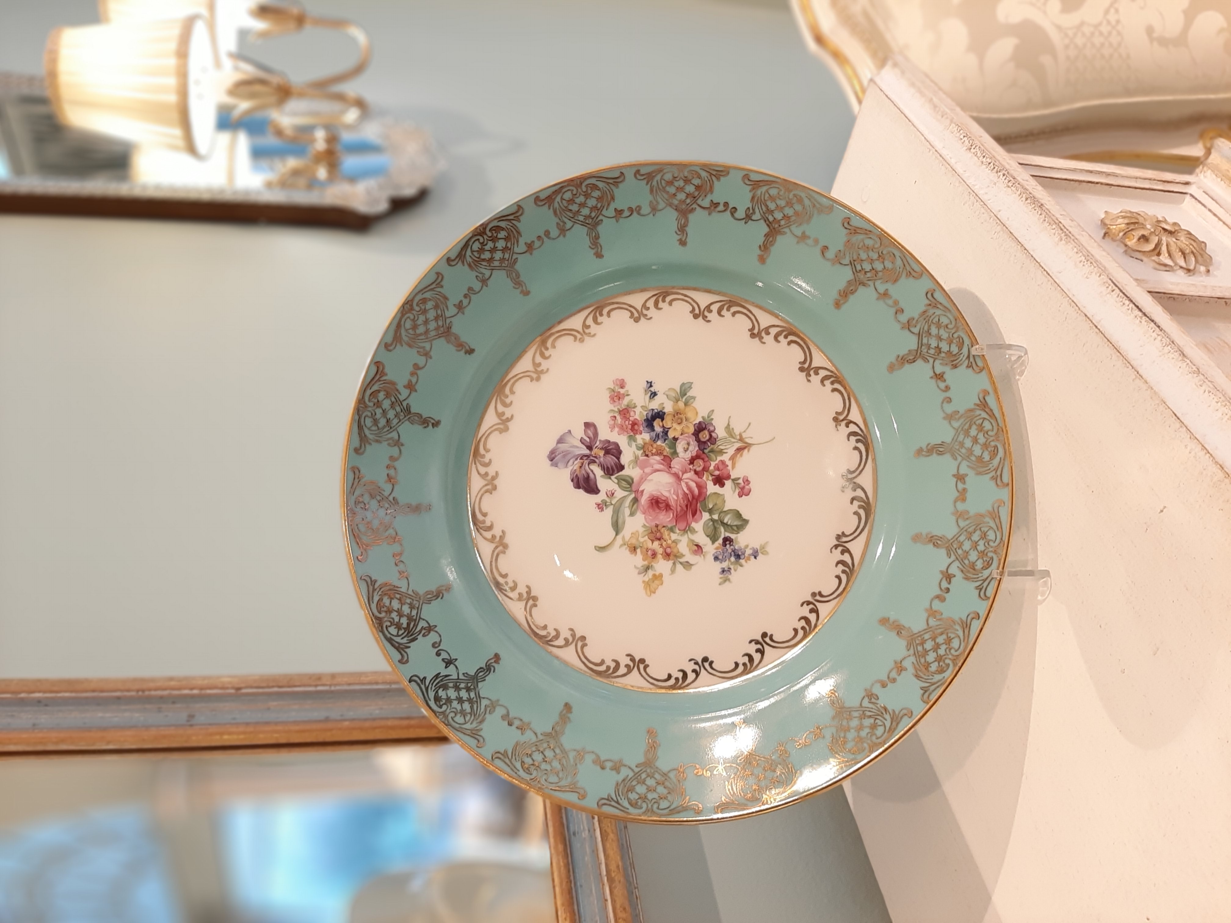 Farbenfroher handbemalter Teller in Türkis mit floraler Malerei, dekorativ aufgestellt